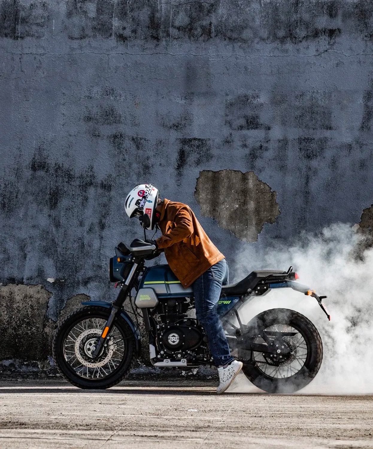 A 2022 Royal Enfield Scram 411 motorcycle does a burnout in an urban environment