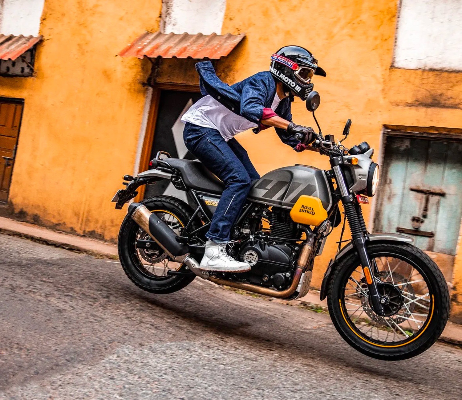 A 2022 Royal Enfield Scram 411 motorcycle jumps off of a speed bump in the city