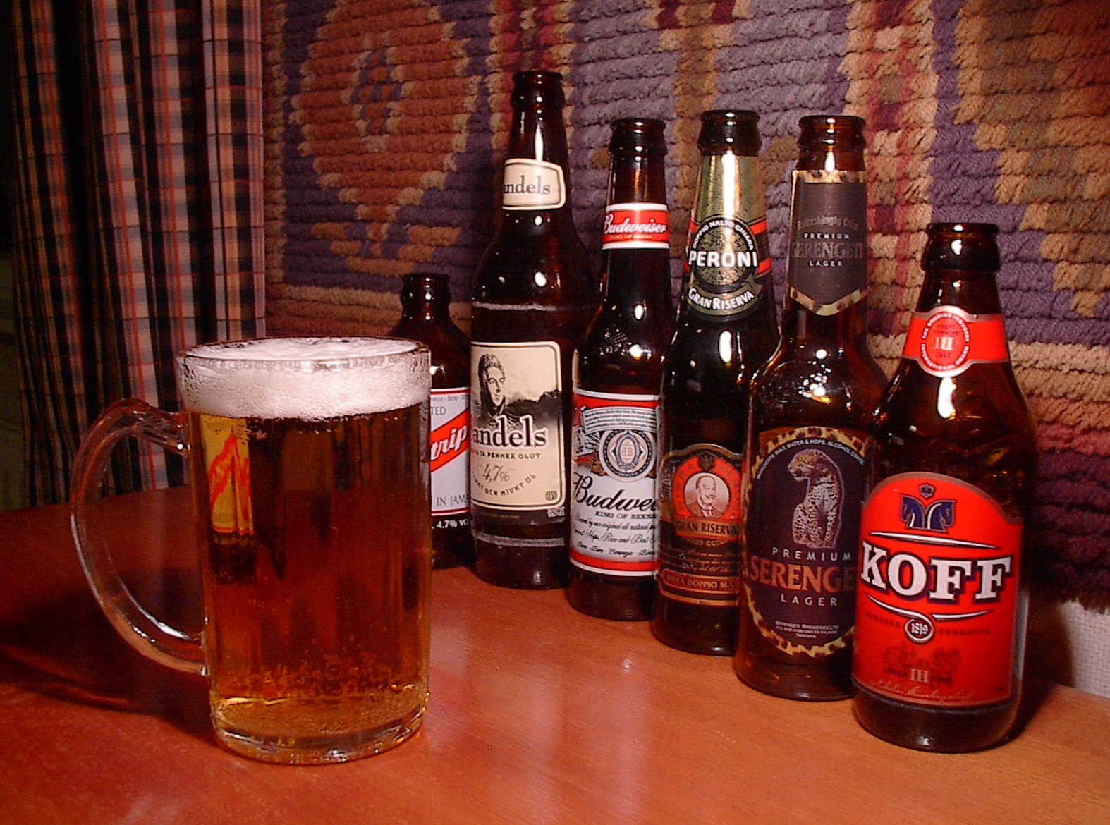 Glass_of_beer_with_bottles_in_the_background.jpg