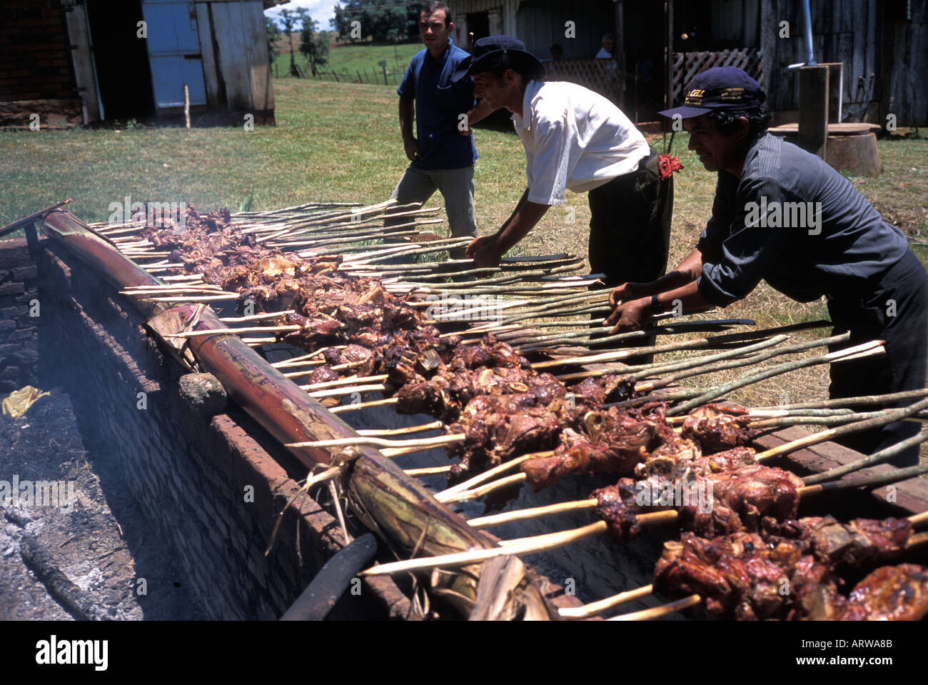 paraguayan-men-preparing-meat-on-skewers-over-a-parrilla-a-barbeque-ARWA8B.jpg