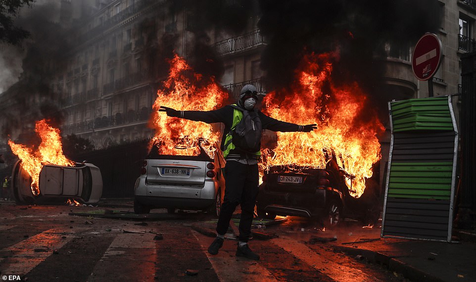 6886990-6449407-A_Yellow_Vest_protester_stands_in_front_of_three_burning_cars_af-m-36_1543686850566.jpg